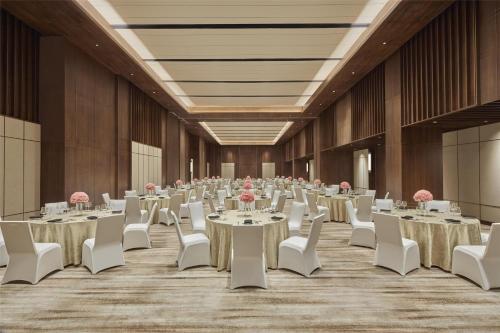 a banquet hall with tables and white chairs and pink flowers at Hilton Gurugram Baani City Centre in Gurgaon