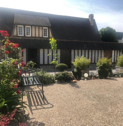 une maison avec un banc dans une cour fleurie dans l'établissement Maison charmante en Normandie, à Montivilliers