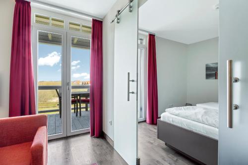 a bedroom with a bed and a view of a table at Resort Deichgraf Resort Deichgraf 31-13 in Wremen