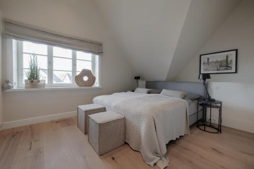 a white bedroom with a bed and a window at Haus Strandhafer in List