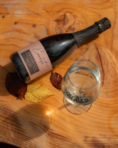 a bottle of wine and a glass on a wooden table at Locanda Al Cacciatore in Nervesa della Battaglia