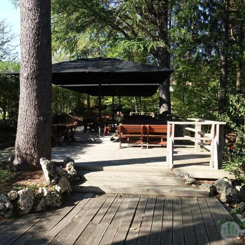 a wooden boardwalk with benches and a black umbrella at Locanda Al Cacciatore in Nervesa della Battaglia