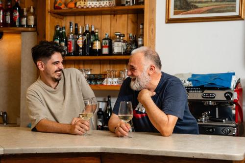 two men sitting at a bar with glasses of wine at Locanda Al Cacciatore in Nervesa della Battaglia