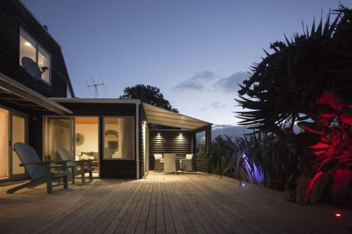a house with a deck with a bench on it at Chester Cottage Beachfront - direct ocean access in Oakura