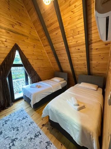 a bedroom with two beds in a wooden cabin at Azhara Bungalow in Soğuksu