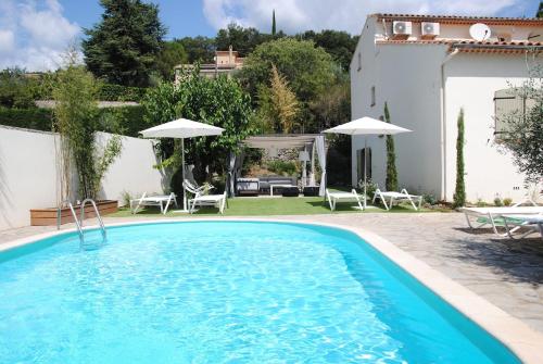 - une piscine avec des chaises et des parasols à côté d'une maison dans l'établissement Villa 12 couchages avec piscine, à Anduze
