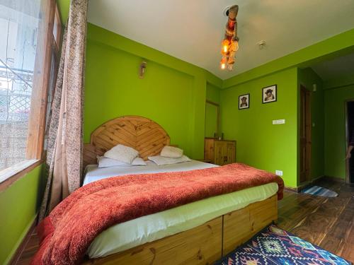 ein grünes Schlafzimmer mit einem Bett mit einem hölzernen Kopfteil in der Unterkunft Jack of all in Manali