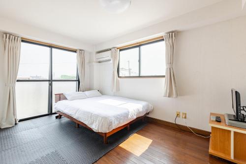 福冈Fieldnever Apartment STAY - Maisonette Family room的一间卧室设有一张床和两个大窗户