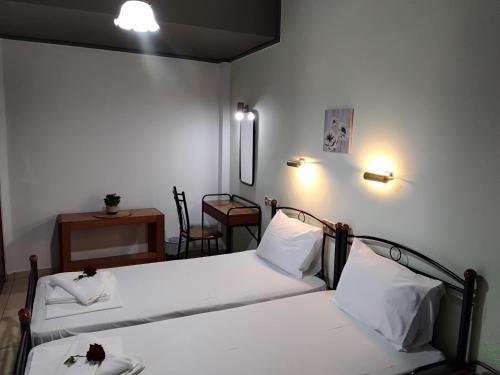 two beds in a room with a table and a chair at Hotel Tainaro in Loutra Edipsou