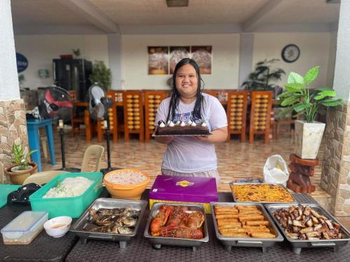a woman holding a cake in front of a buffet at Julz Ridge Exclusive Place in Bayombong in Bayombong