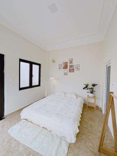 a white bedroom with a large bed and a window at Mập's Soul Hostel Đà Lạt in Da Lat