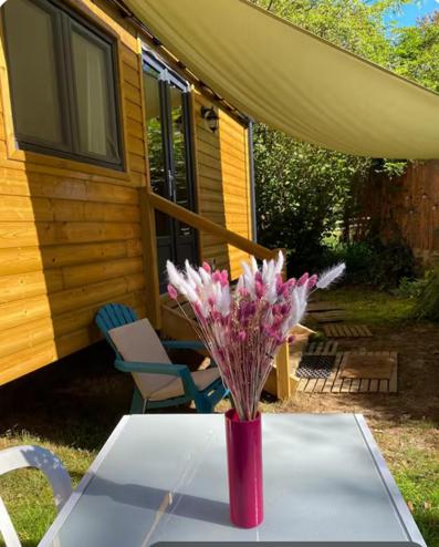 un vase de fleurs sur une table devant une maison dans l'établissement La tiny house, à Saint-Vincent-de-Paul