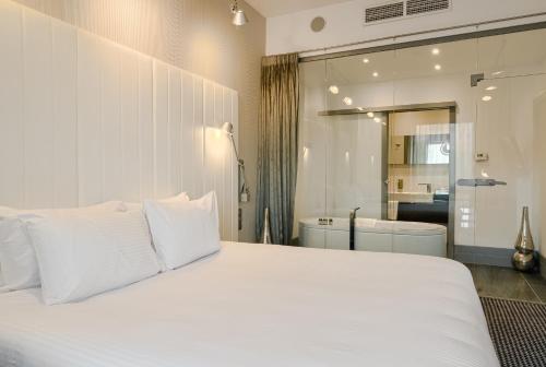 a bedroom with a large white bed and a bathroom at Qubus Hotel Bydgoszcz in Bydgoszcz