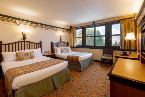 Una habitación de hotel con dos camas y un escritorio. en Disney Sequoia Lodge, en Coupvray