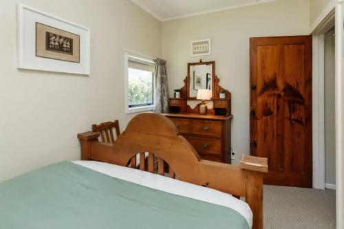 a bedroom with a bed and a dresser and a mirror at Messenger Magic - classic 5BR Kiwi bach in Oakura