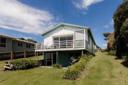 a house with a balcony on a lawn at Messenger Magic - classic 5BR Kiwi bach in Oakura