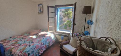 une chambre avec un lit, une chaise et une fenêtre dans l'établissement La maison du pêcheur, à Collioure