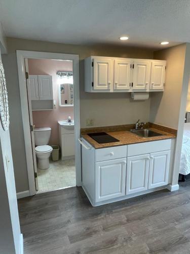 a kitchen with white cabinets and a sink and a toilet at The Braemar Condominium in North Truro