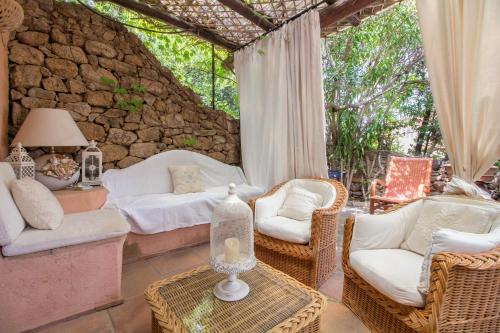 a living room with wicker furniture and a stone wall at GuestHost - Porto Cervo Liscia di Vacca Apartment in Liscia di Vacca