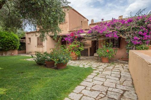 a house with flowers and plants in a yard at GuestHost - Porto Cervo Liscia di Vacca Apartment in Liscia di Vacca