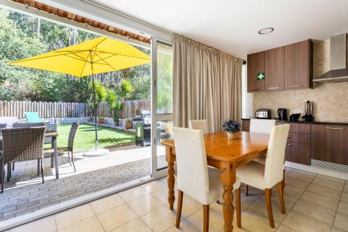 a kitchen and dining room with a wooden table and yellow umbrella at Rural Natura in Leiria