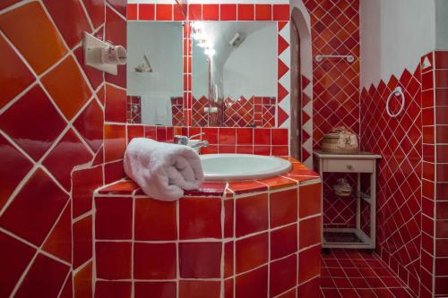 a red tiled bathroom with a sink and a mirror at GuestHost - Porto Cervo Liscia di Vacca Apartment in Liscia di Vacca