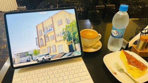 un computer portatile appoggiato su un tavolo con un piatto di cibo e una bevanda di LeLodge Djibouti a Gibuti