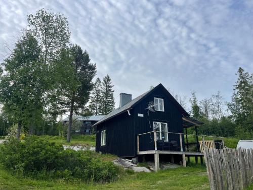 a black house with a deck in a field at Grindstugan in Sandöverken
