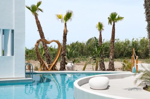 a swimming pool with palm trees in the background at Martini Boutique Resort in Ialyssos