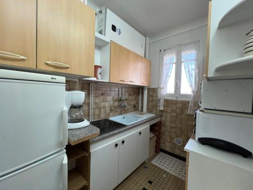 une cuisine avec un réfrigérateur blanc et un évier dans l'établissement Studio vue mer avec loggia et parking, à Saint Cyprien Plage