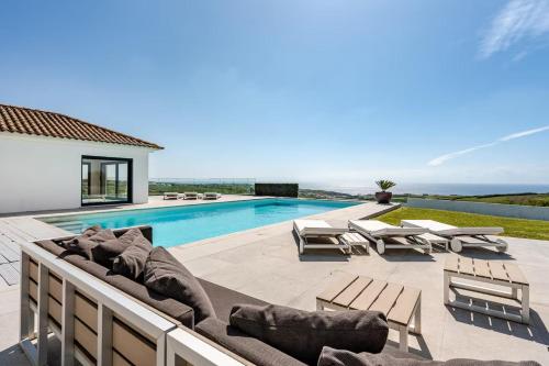 a villa with a swimming pool and a patio with lounge chairs at Bica Vista in Lourinhã