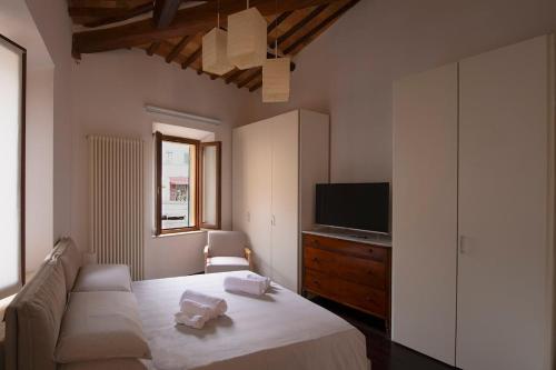 Un dormitorio con una cama, un televisor y un sofá. en La casa di Annetta, en Montalcino