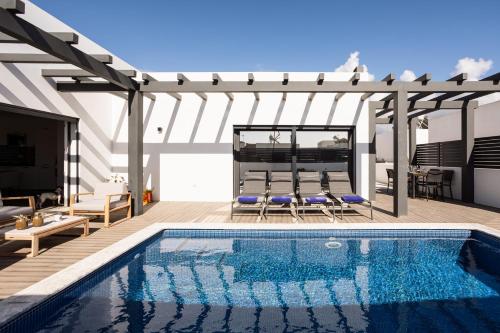 a swimming pool in a patio with a pergola at Villa Sal - Porto Covo in Porto Covo