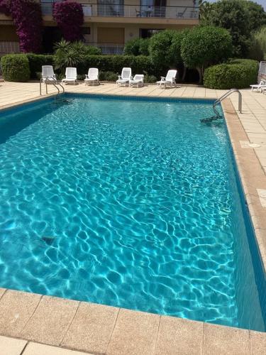 une grande piscine bleue avec des chaises dans un bâtiment dans l'établissement Belle résidence arborée, Appart climatisé, piscine, à 500m de la mer, à Sainte-Maxime