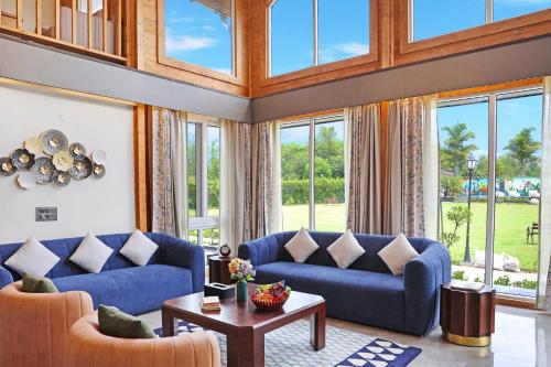 a large living room with blue couches and windows at Luxury 4BHK with Garden Pool and Entertainment Space in Palāhu