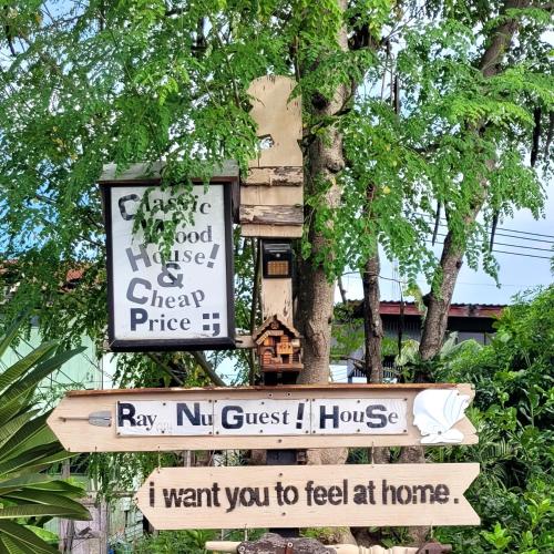 a sign hanging from a tree with some signs at Ray Nu Guest House in Phra Nakhon Si Ayutthaya