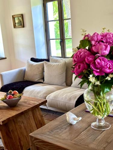 a living room with a couch and a vase of flowers on a table at Château De La Bûcherie in Saint-Cyr-en-Arthies