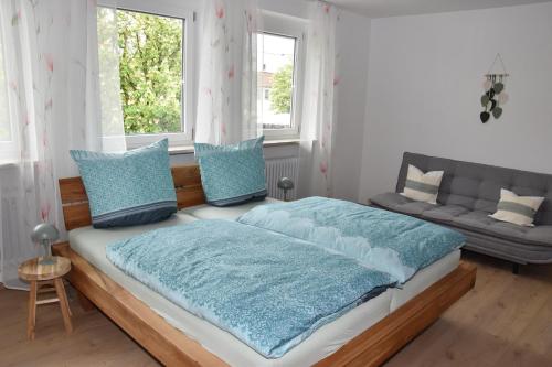 a bedroom with a bed with blue pillows and a couch at Ferienwohnung Eder in Bad Birnbach