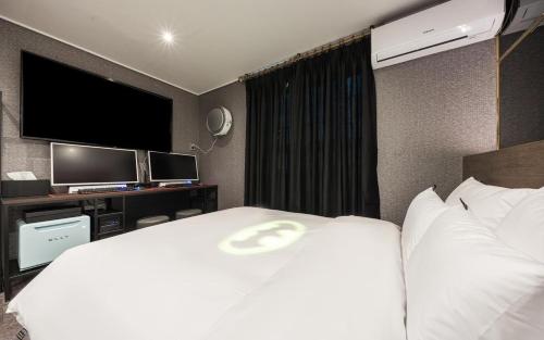a hotel room with a white bed with a flat screen tv at Hotel Ravi in Seoul