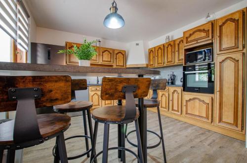 une cuisine avec des placards en bois et des tabourets de bar dans l'établissement Aux souvenirs d'enfance, à Piney