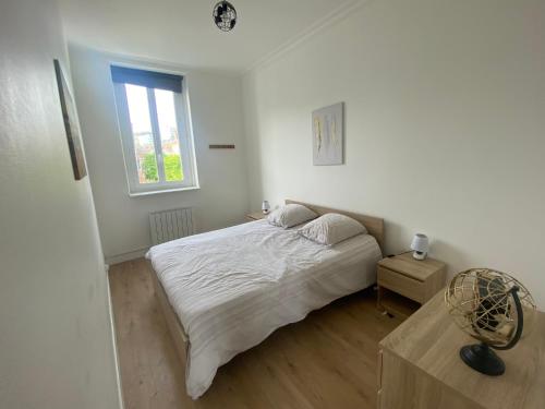 une chambre blanche avec un lit et une fenêtre dans l'établissement L'embrun Fécampois, à Fécamp