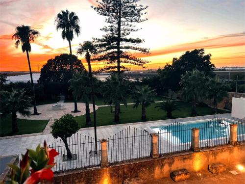 a view of a pool and palm trees at sunset at Villa Maggio in Acate