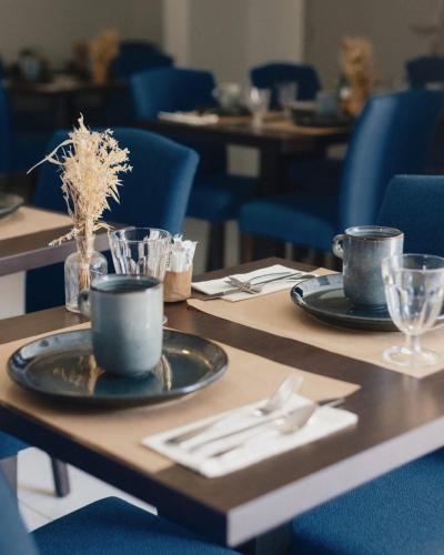 a wooden table with plates and silverware on it at Le Nautica Hôtel in Perros-Guirec