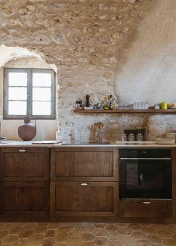 a kitchen with wooden cabinets and a window at Château De La Bûcherie in Saint-Cyr-en-Arthies