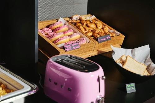 a table with a pink toaster and a box of donuts at Moxy Warsaw City in Warsaw