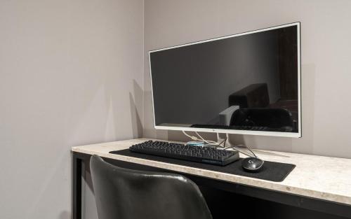 a computer monitor and a keyboard and mouse on a desk at Hotel AND in Suwon