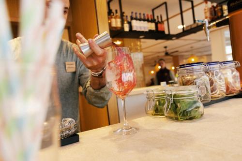 a woman standing behind a counter with a wine glass at Caramelo Marina Calan Bosch - Adults Only in Cala en Bosc