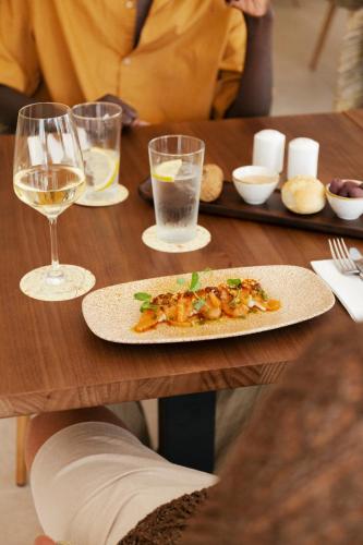 a table with a plate of food and glasses of wine at Caramelo Marina Calan Bosch - Adults Only in Cala en Bosc