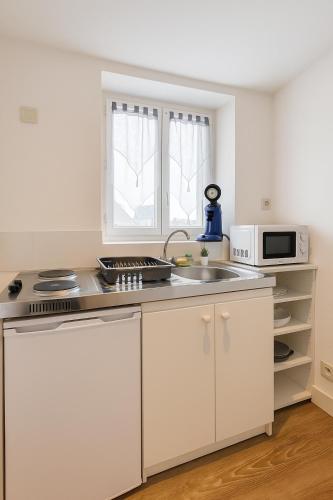 une cuisine blanche avec un évier et un micro-ondes dans l'établissement Le Cozy - Hyper centre - Calme - Moyenne durée, à Épinal