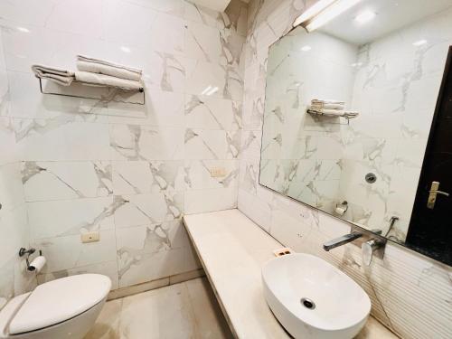 a white bathroom with a toilet and a sink at The South Manor Residency Near AIIMS Hospital New Delhi in New Delhi